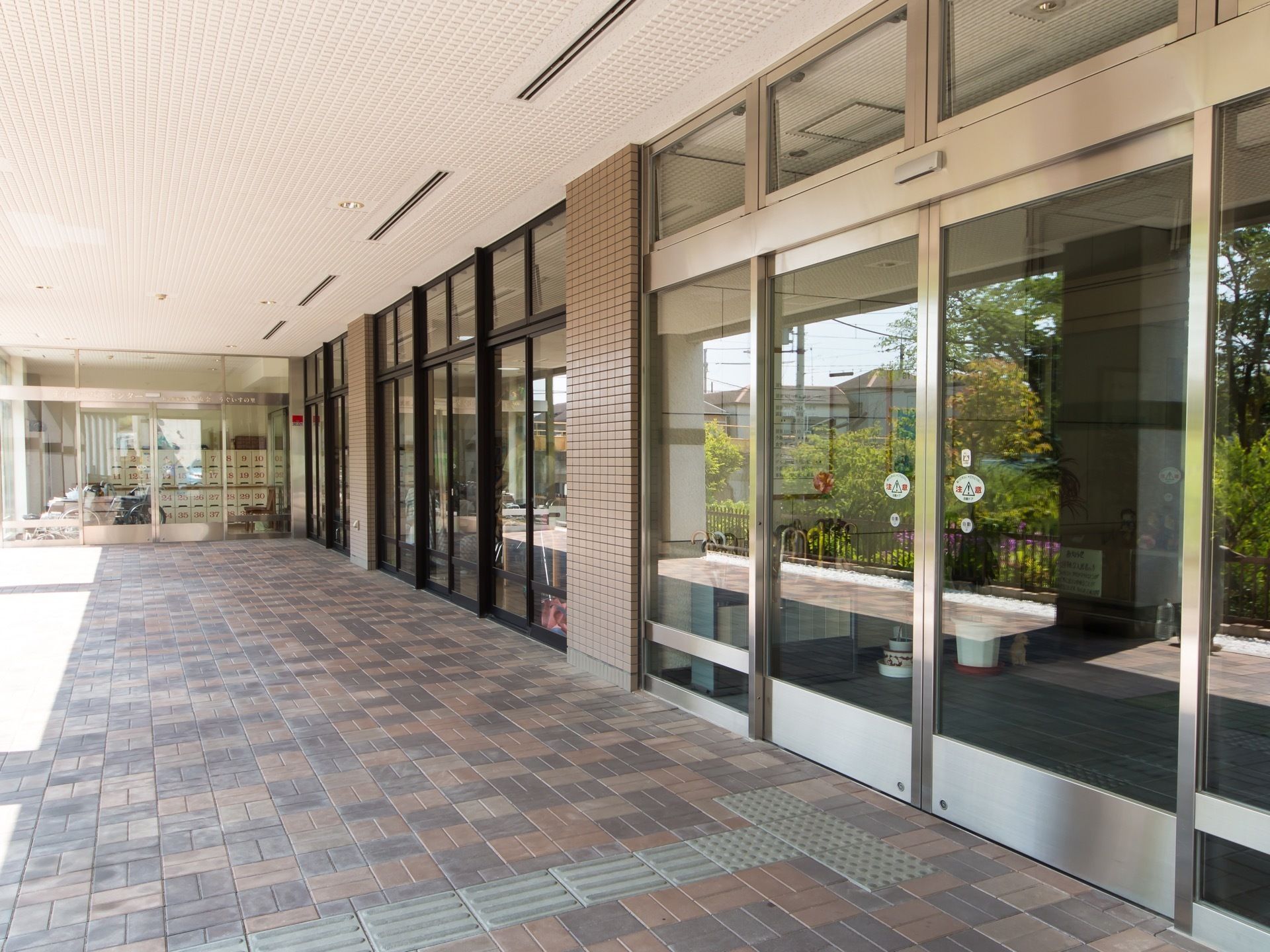 大きな自動ドアを設置した玄関である。壁や天井にタイルが敷き詰められて、入口までは点字ブロックも埋め込まれている。