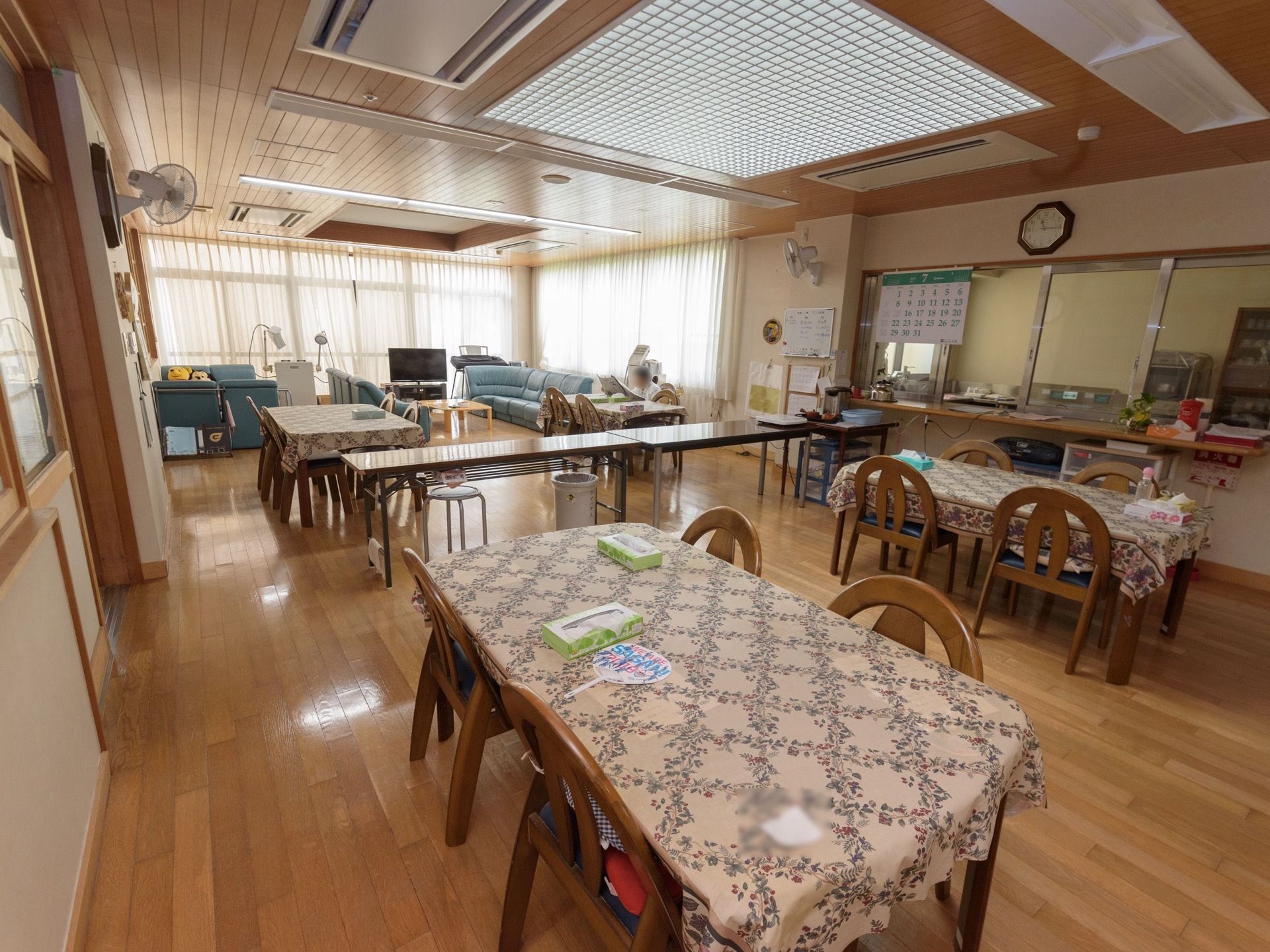 花柄のテーブルクロスが掛けられた、4人掛け用のテーブルセットが設置されている食堂である。奥にキッチンが完備されている。