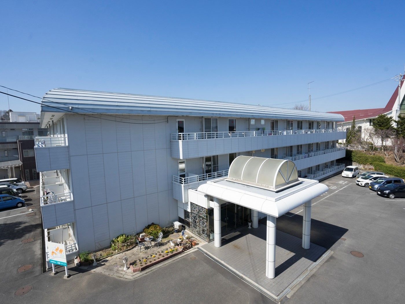 3階建ての建物は白でまとめられていて、玄関には大きな屋根が付いている。