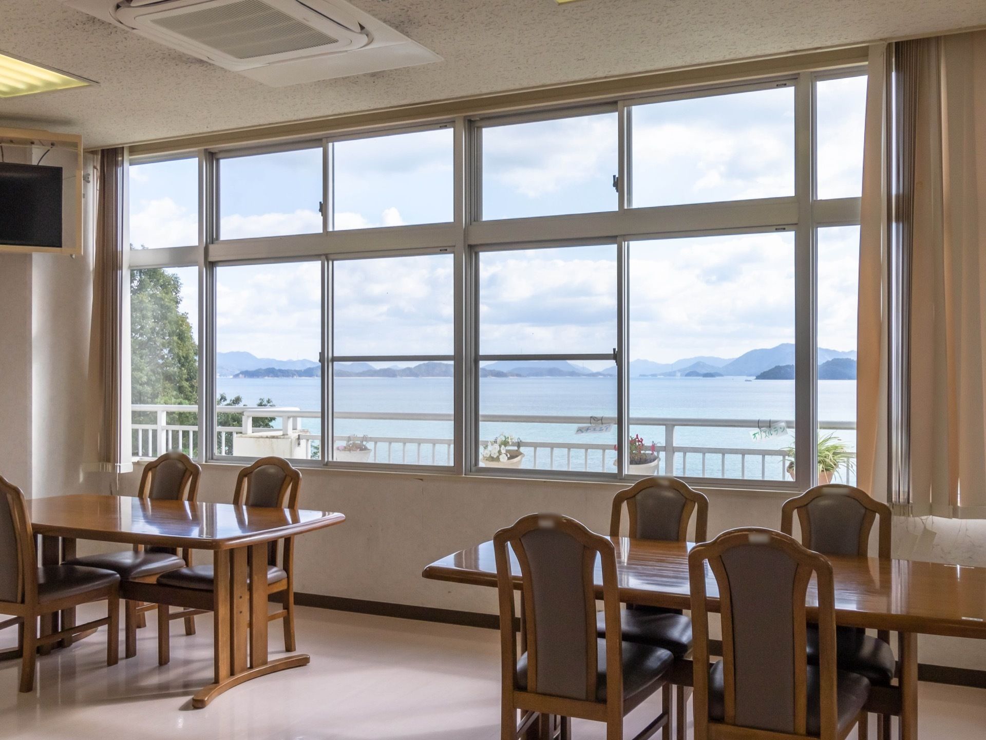 空調設備が整っている食堂で、上部にテレビが１台設置されている。窓からは、広々とした海や自然を望むことができる。