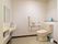 洗面台が備え付けられているトイレで、ハンドソープや消毒液が置かれている。壁にはL字型の手すりがある。