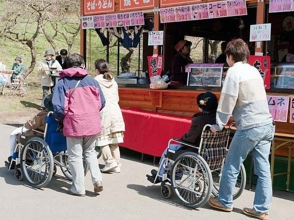 スタッフの介助を受けながら外出を楽しむ車いすの入居者たちの姿。