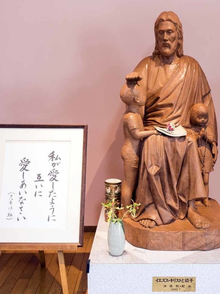 花とイエスの言葉が書かれた額が横に飾られたイエス像。
