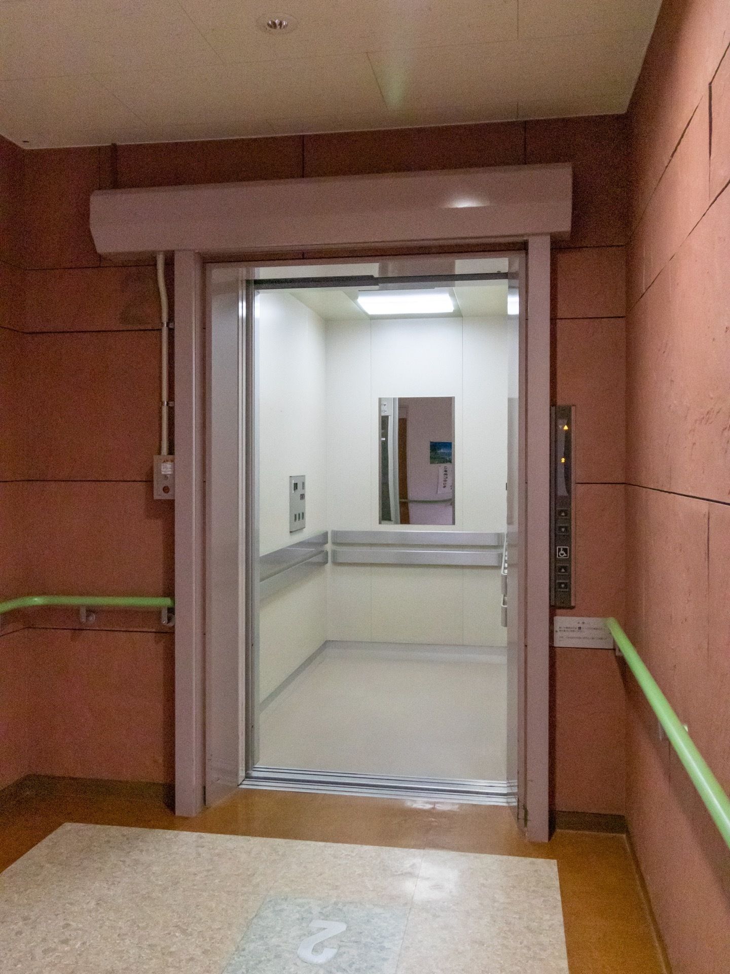 施設にはエレベーターがある。内部には鏡がついており、乗降口の周囲には緑色の手すりが付けられている