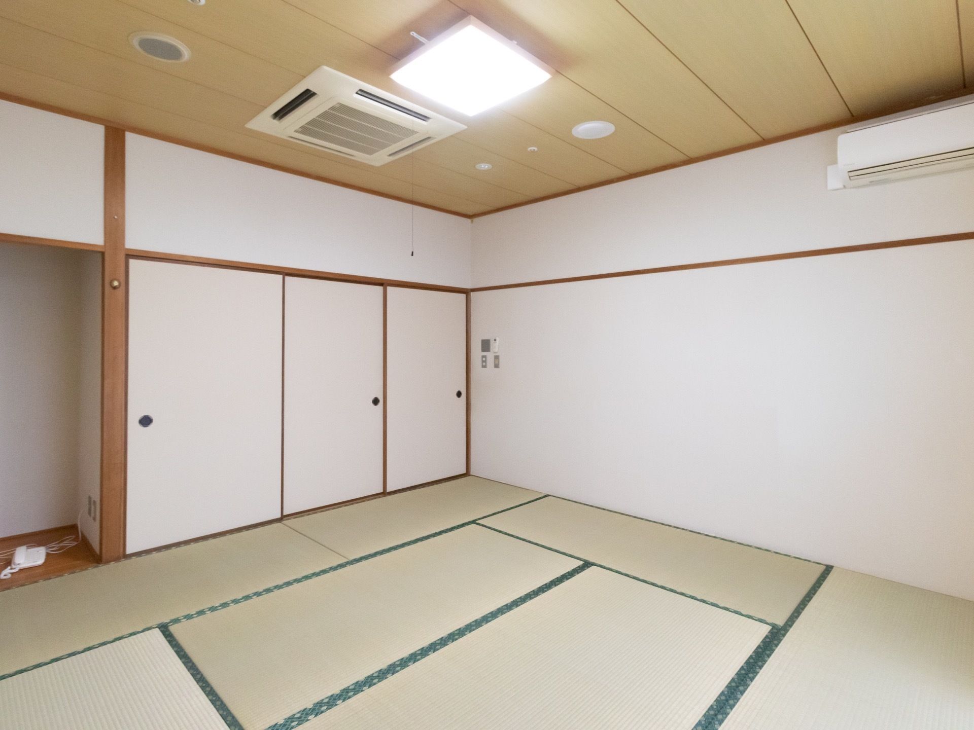 畳が敷かれた和室である。襖と床の間があり、床の間には白い電話機が置いてある。天井に近い位置にエアコンが設置されている。