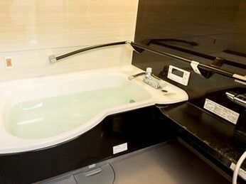一人用の浴槽が設置された浴室はモノトーンカラーでまとめられ、浴槽のそばにはオレンジの呼び出しボタンが付いている。