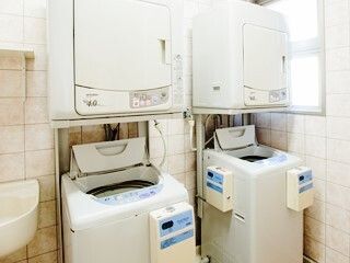 縦型の洗濯機と乾燥機がペアで２組置かれているランドリースペースには大き目の窓があり、明るい雰囲気。手洗いで洗う場所もある。