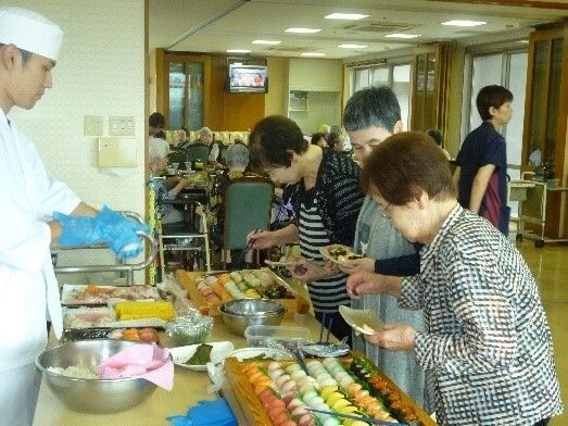 すし飯を薄焼き卵で巻き、鶉卵を顔に見立ててひな人形の形にしている。赤い盆の上にはフルーツやおかずも盛られ華やかな一品。