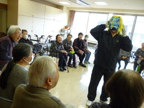 鬼のお面をかぶった鬼役の人ととそれを囲む人たちによるレクリエーションの風景