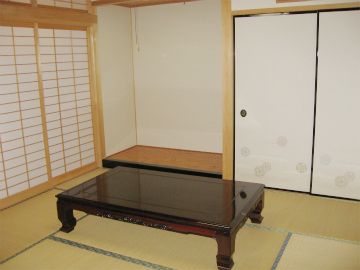 大きな和風のテーブルが置かれた畳敷きの和室には、床の間があるが、何も置かれていない。