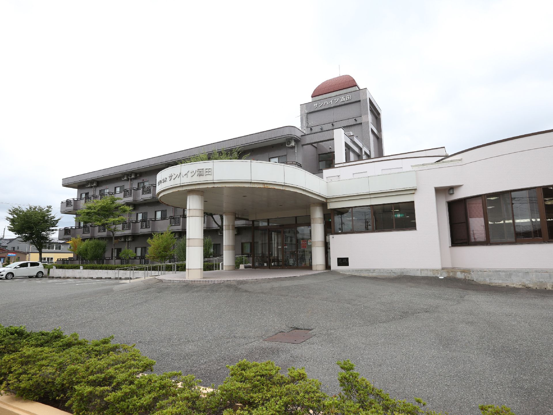 広い敷地に建っている、屋上の赤色の構造物が特徴的な施設外観