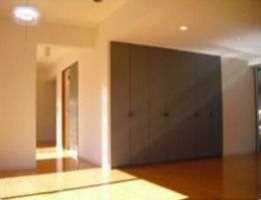 広々とした芝生が敷かれた庭がある3階建ての建物。グレーの外壁でベランダがあり、各居室の窓の内側にはカーテンがある。
