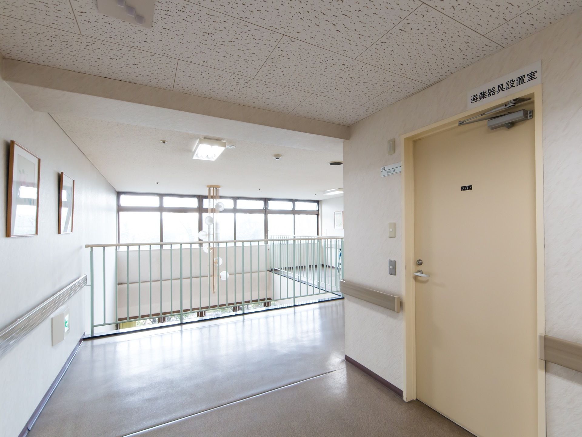 エントランスホールの吹き抜けを囲むようにフェンスが設置してある。右側には、避難器具設置室の開き戸がある。