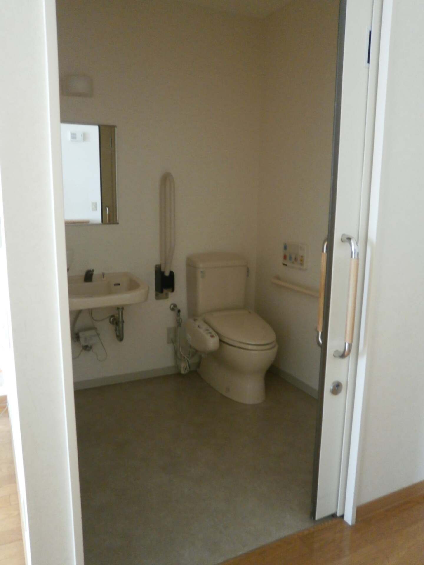 手すりが両サイドに付いたトイレは介助スペースが広く、鏡が付いた手洗い場も付いている。