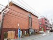 公道沿いに地上4階建てのレンガ調の施設が建っている。広い歩道があり、ゴミ収集所やバス停が設けられている。