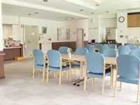 広めの施設内に緑色の椅子と机が並んでいる様子。施設内の食堂スペース