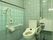 トイレには温水洗浄便座のついた、洋式便器を設置している。壁には操作パネルがあり、手すりがある。