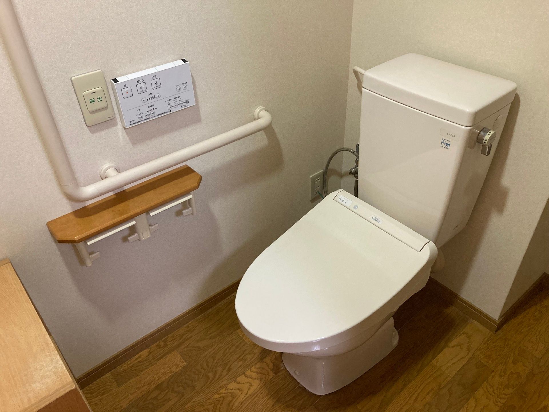 エル字型の手すりや呼び出しボタンも設置されたトイレは洋式で居室との間に段差はない。
