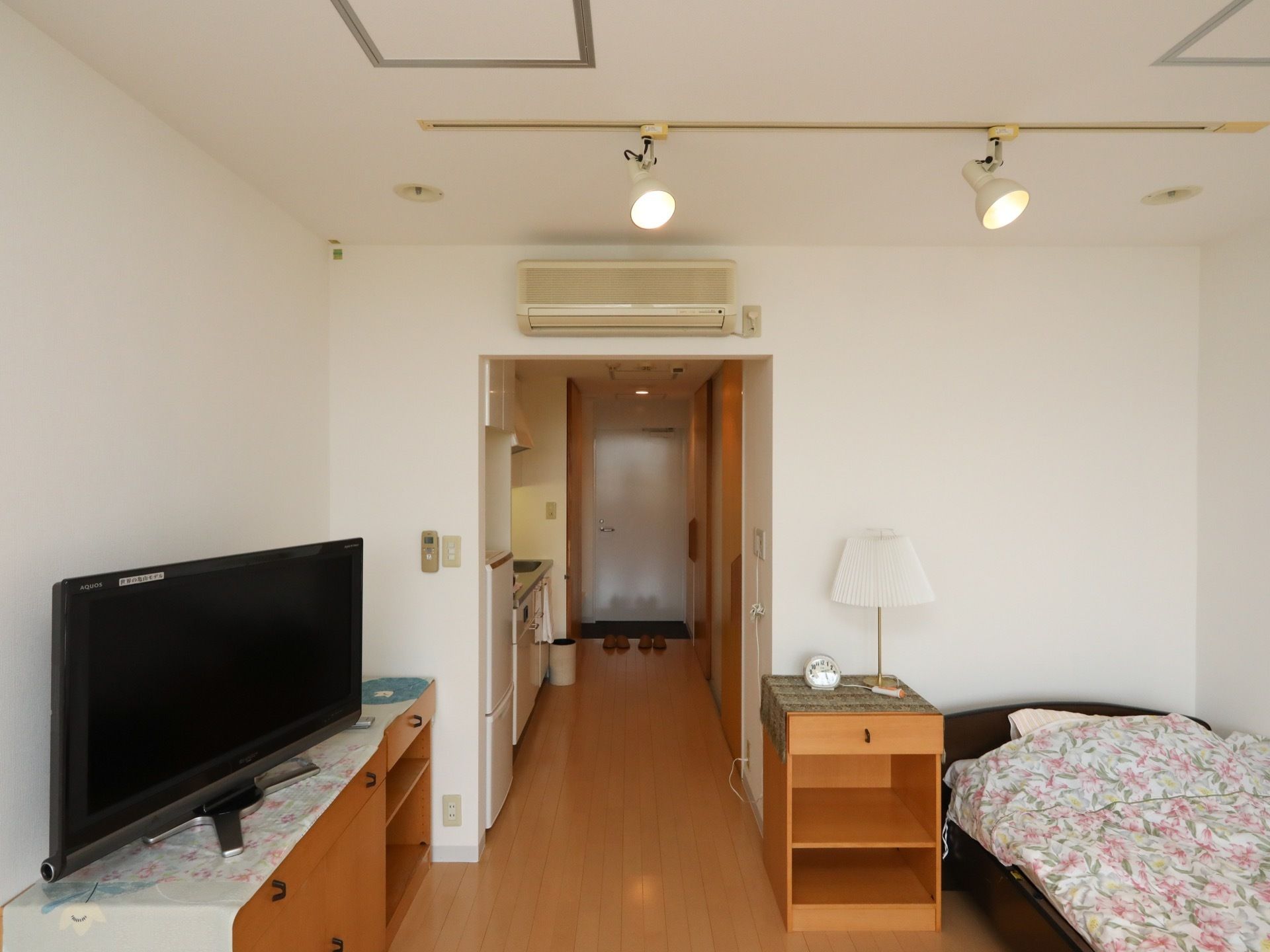 １人用の居室である。コンパクトキッチンやエアコン、照明が完備されている。壁際には、ベッドがある。