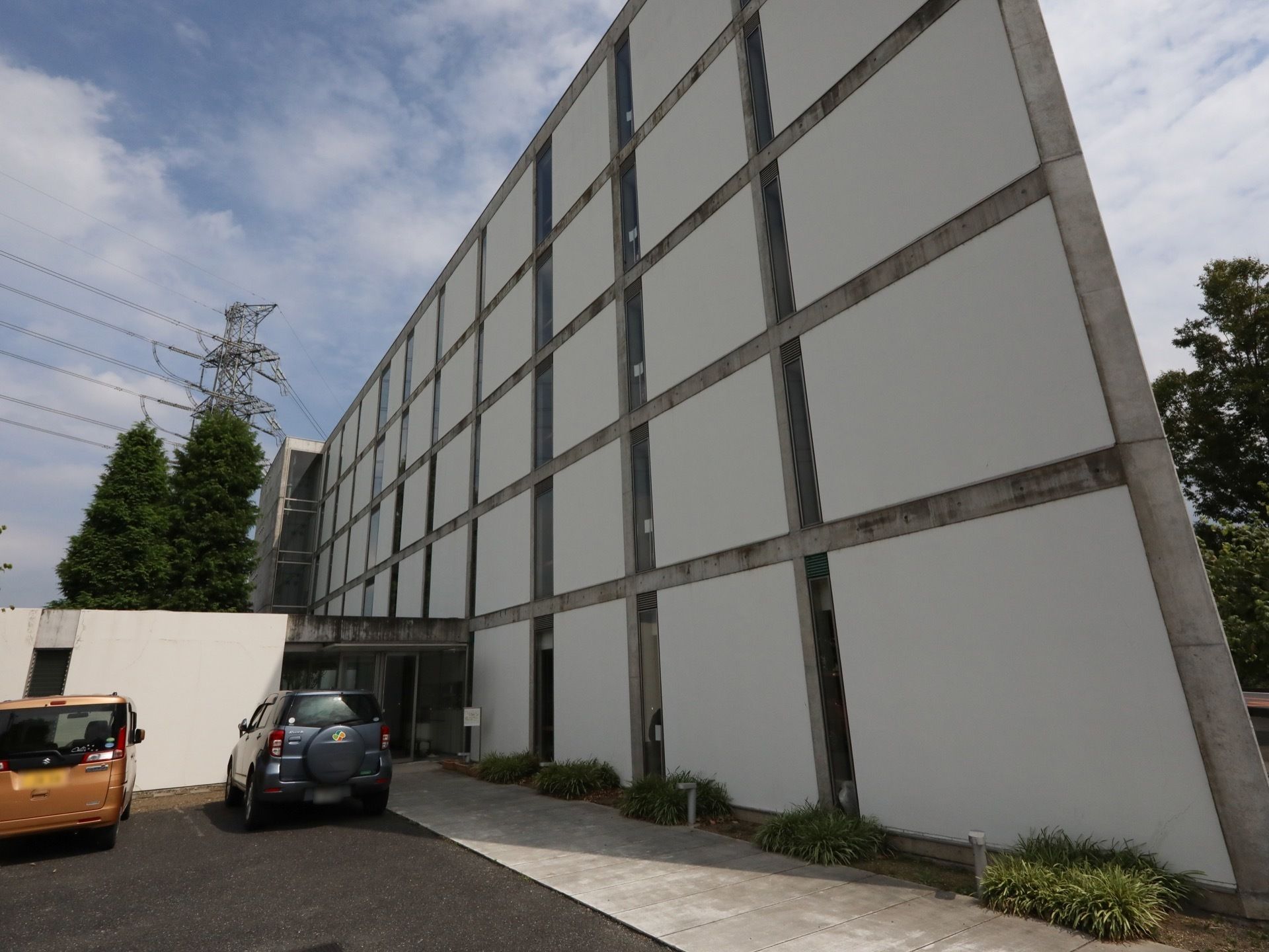 玄関アプローチには、建物に沿って長方形のブロックが敷かれている。足元に近い位置に外灯がある。左側は駐車場である。