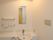洗面台が居室のトイレに完備されている。鏡や棚、コンセントが壁に備え付けられており、天井に照明がある。
