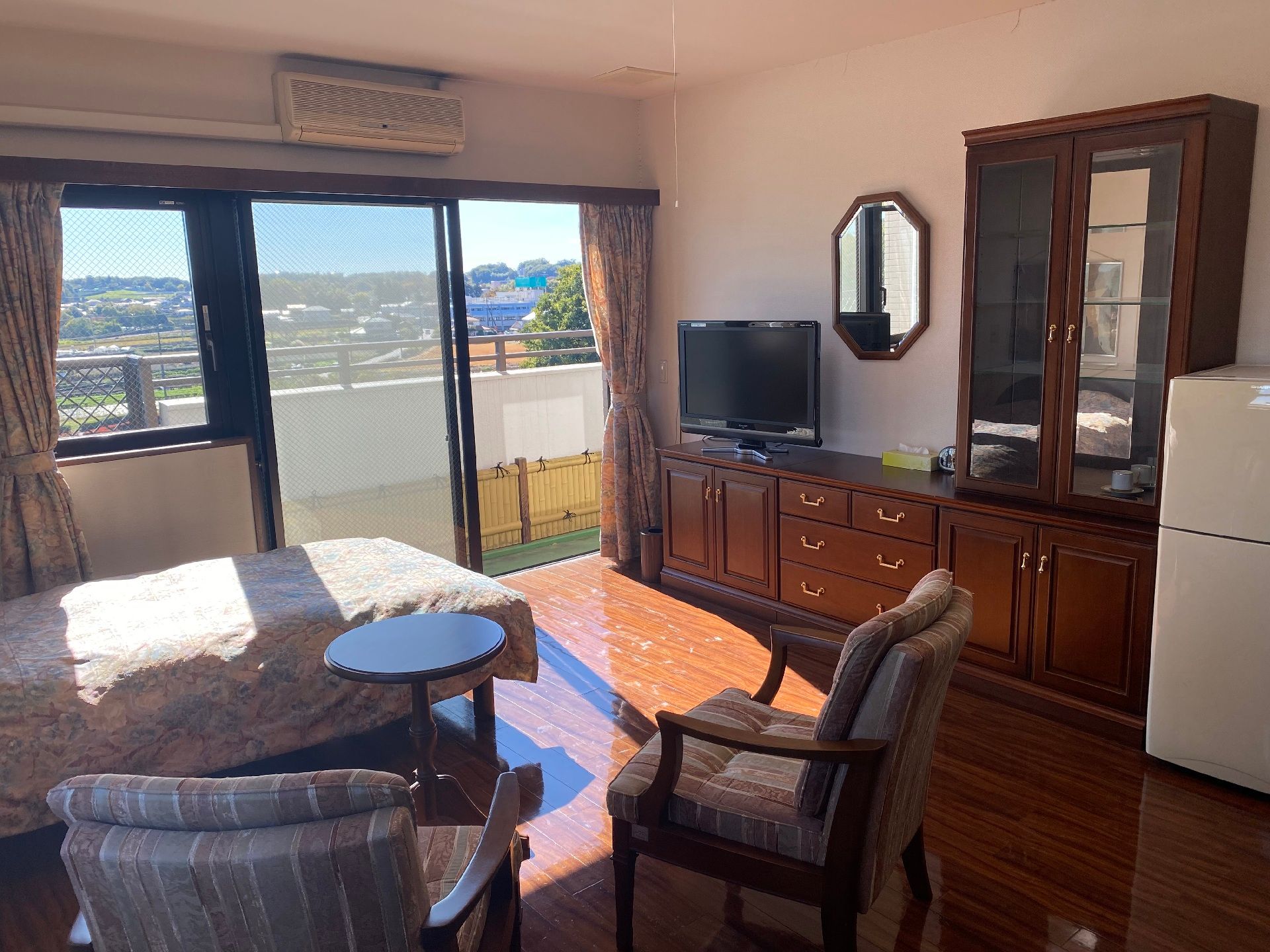 白衣を着た女性スタッフがベージュのソファに座っている高齢女性たちと楽しそうに話している。