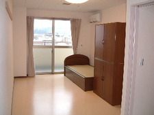 一人用の小さな部屋にベッドとタンスが置いてある様子。オールバリアフリーの部屋の中を写した写真