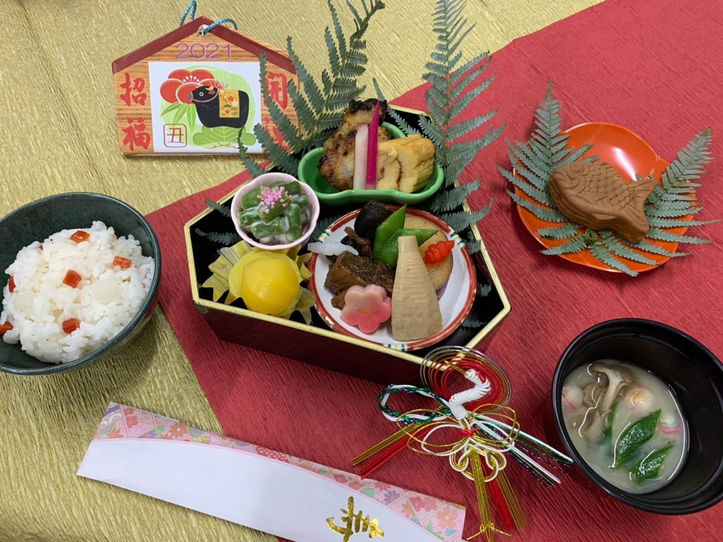 栗きんとんや野菜の煮物、卵焼きやごはんと味噌汁、デザートのたい焼きが付いたメニュー