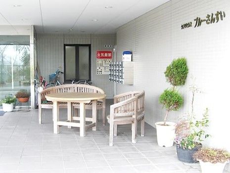 広々とした玄関周辺にはゆったりとしたベンチとテーブルが置かれ、季節の木々が鉢植えで置かれている。