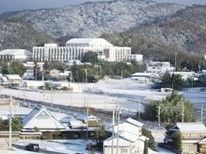 周辺の冬景色。雪が降り、奥には山が手前には住宅が点在している。