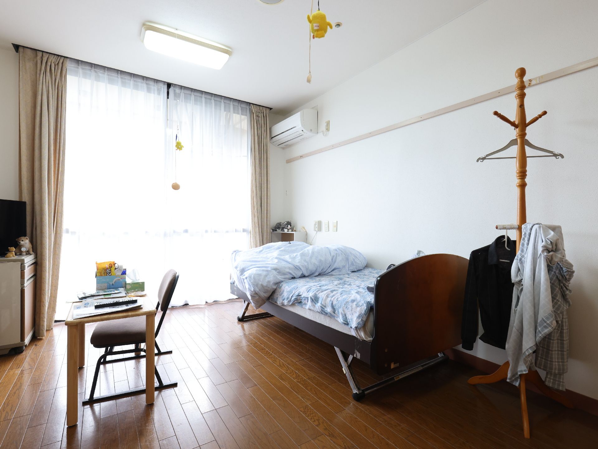 窓から日差しが入り、家具や介護ベッドが置かれている居室