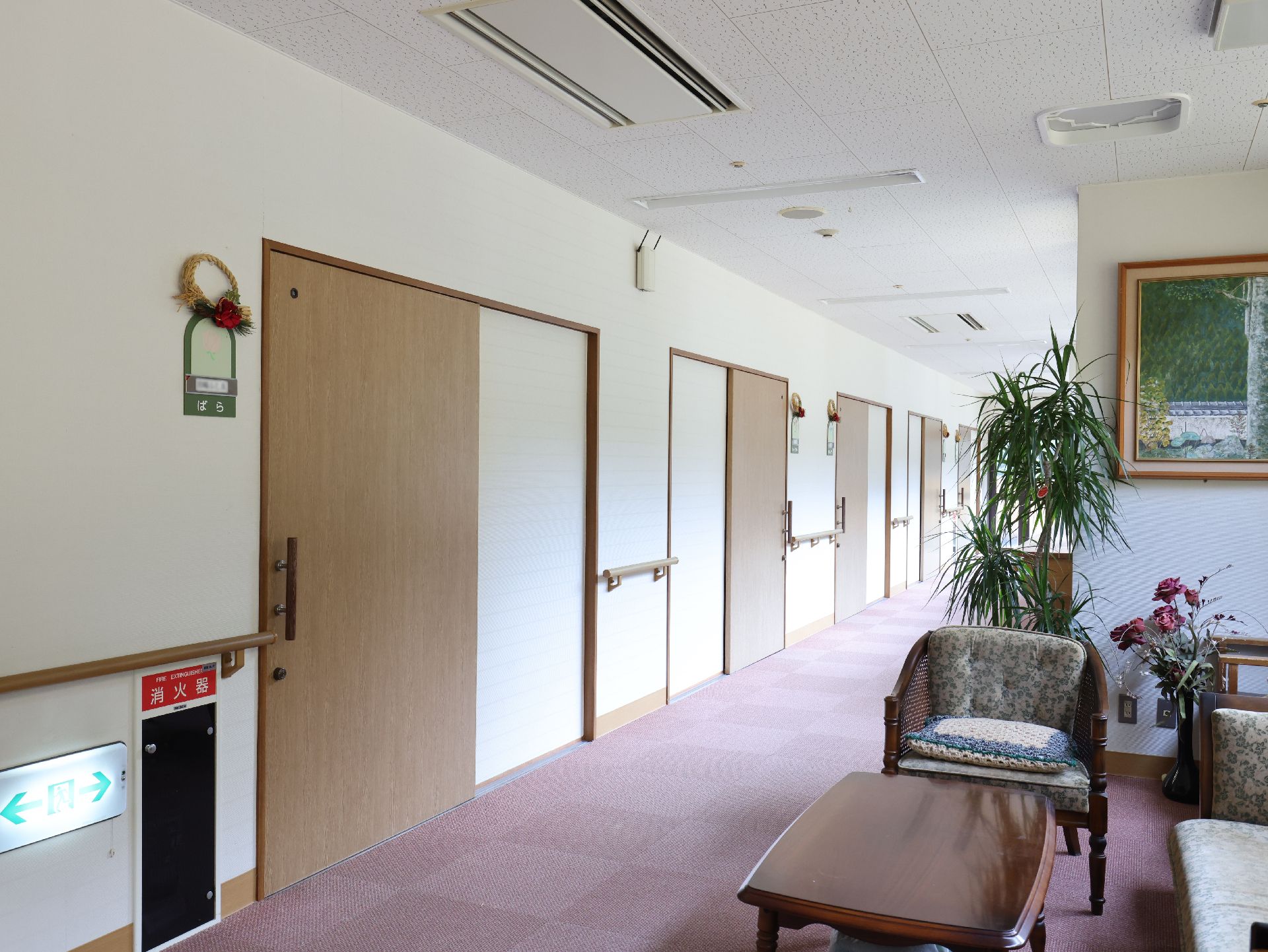 カメラに向かって笑顔を見せるスタッフと高齢者の女性。施設での何気ない一場面の様子