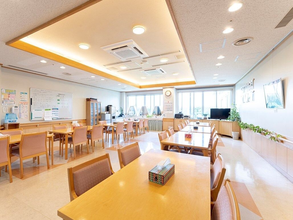 大きなテレビが設置された食堂にはたくさんのダイニングテーブルセットが置かれ、大きな窓から陽の光が入っている。