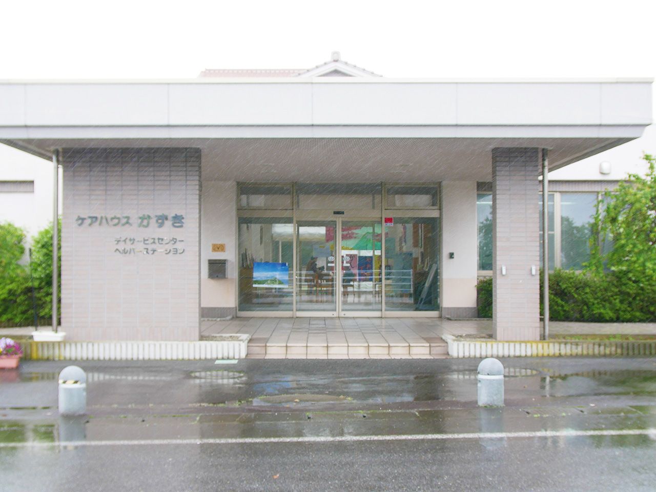 ケアハウスかずきと書かれたベージュの外壁の3階建てケアハウス
