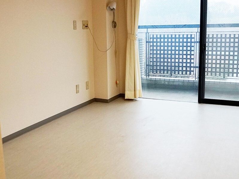 カーテンが付いている大きな窓があるフローリングの部屋にはバルコニーもあり、家具などは置かれていない。