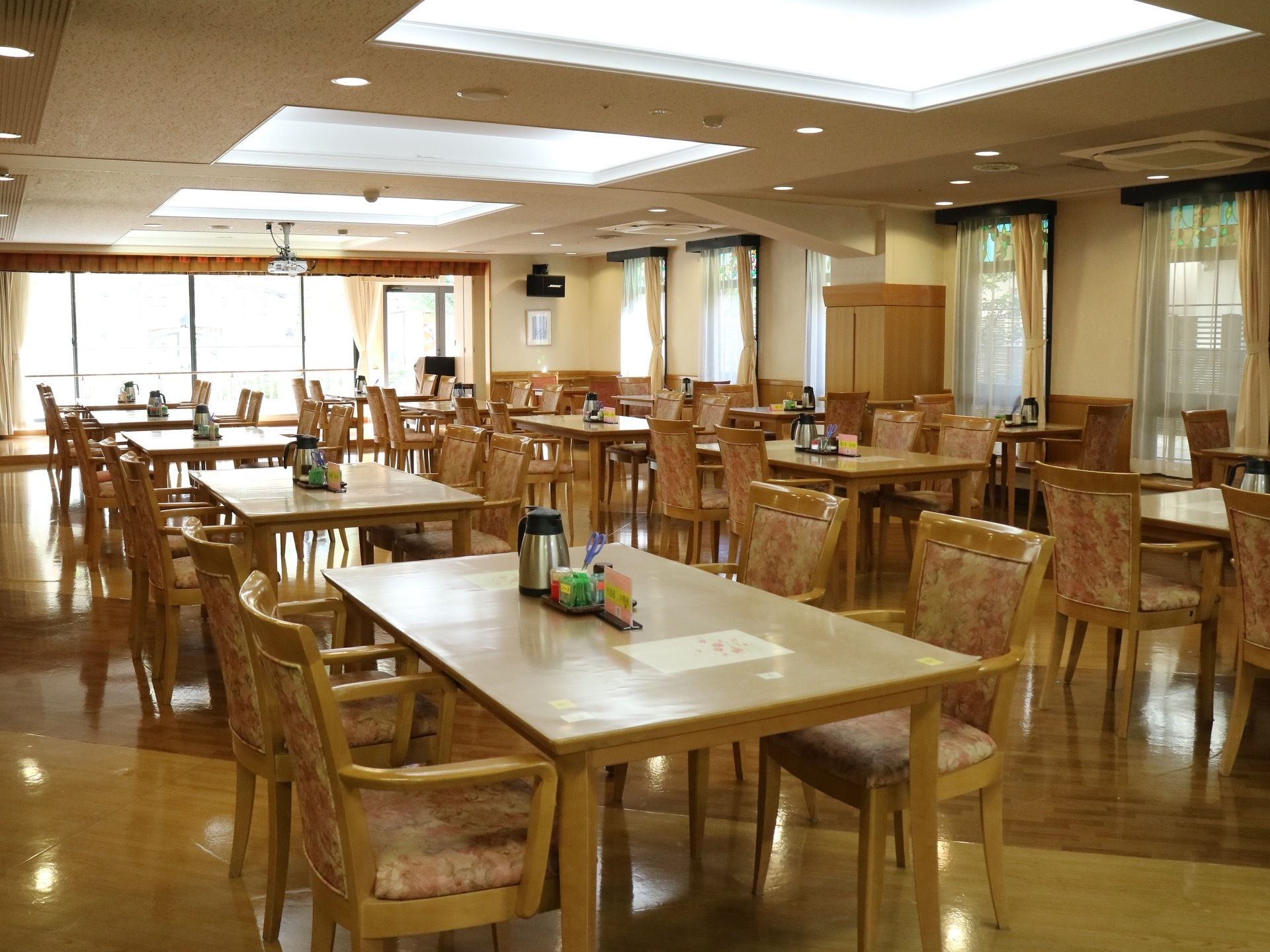 窓が大きく外からの光で空間を明るくなっている共有スペース。室内は広々としているので、入居者様ひとりひとりがゆとりをもって過ごせる。