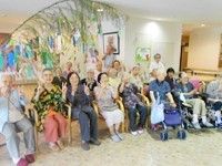 笹の葉がある向こう側に高齢者が車いすに乗って並んでいる様子