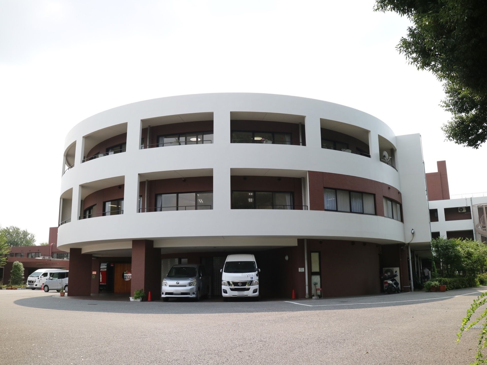 アスファルト舗装の敷地の中に施設建物が建てられている。３階建て構造になっており、１階部分には自動車が収容できる。