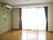 居室内の床はフローリングで、緑の壁にエアコンが取り付けてある。掃き出し窓からベランダに出られるタイプとなっている。