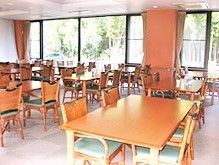 肘置き付きの椅子がセットされた4人掛けのダイニングテーブルが並んだ食堂はカーペット敷き。