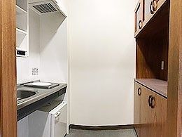 小さな一人用のキッチンスペースが写っている写真。家具類もあるのが分かる