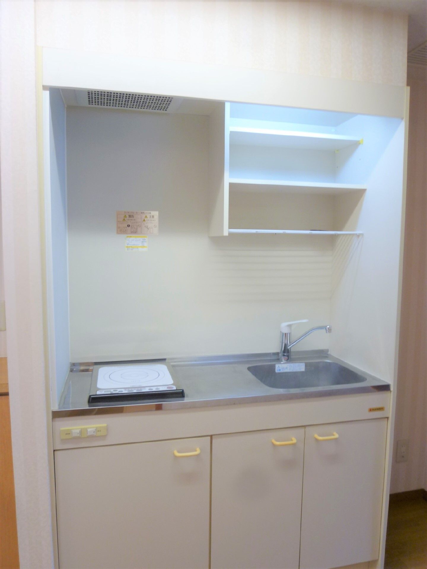 IH調理器の上部に小さな換気扇がついている、居室のユニットキッチン