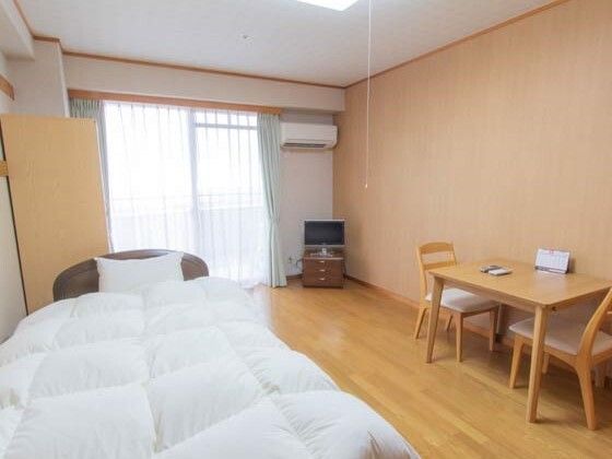 エアコンが設置されたフローリングの部屋には、寝具がセットされたベッドや二人用のテーブルセットが置かれている。