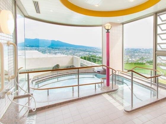 壁一面が窓となっている明るい浴室。階段で出入りするタイプの浴室で、たっぷりのお湯が張られている。