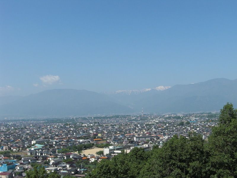 遠方には山々が連なり、手前には多くの住宅がひしめき合う住宅地がある。