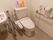 洗面台も併設された広いトイレである。洗浄機能付き便座で、両脇には手すりが設置されている。壁にはナースコールがついている。
