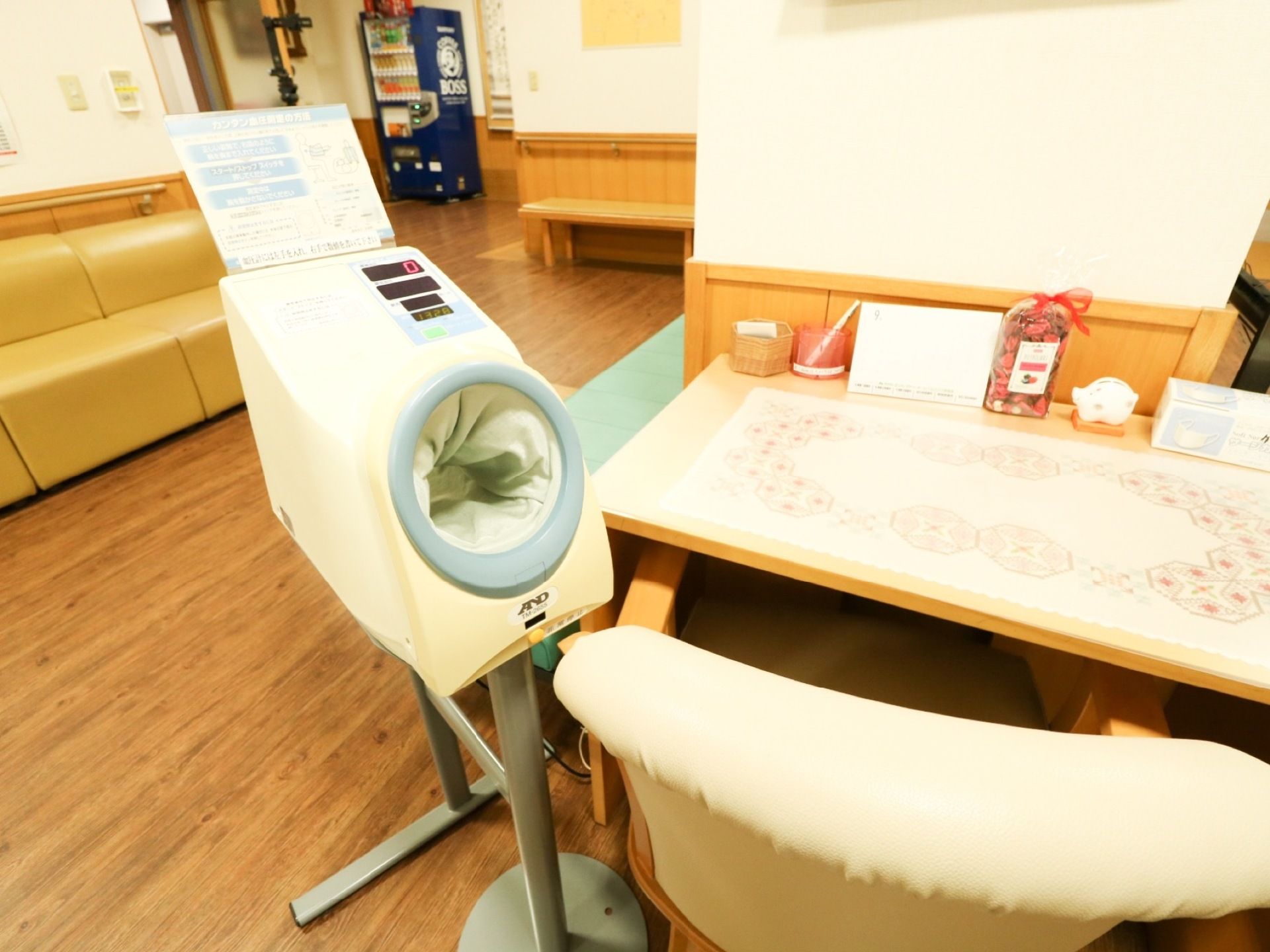 休憩スペースにある机の横に自立式の血圧計がある。使用方法が書かれた紙が血圧計の上に表示されている。