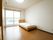 居室の窓の近くにベッドがある。窓の上には木のカーテンレールがかかっている。収納家具が２つ並べられている。