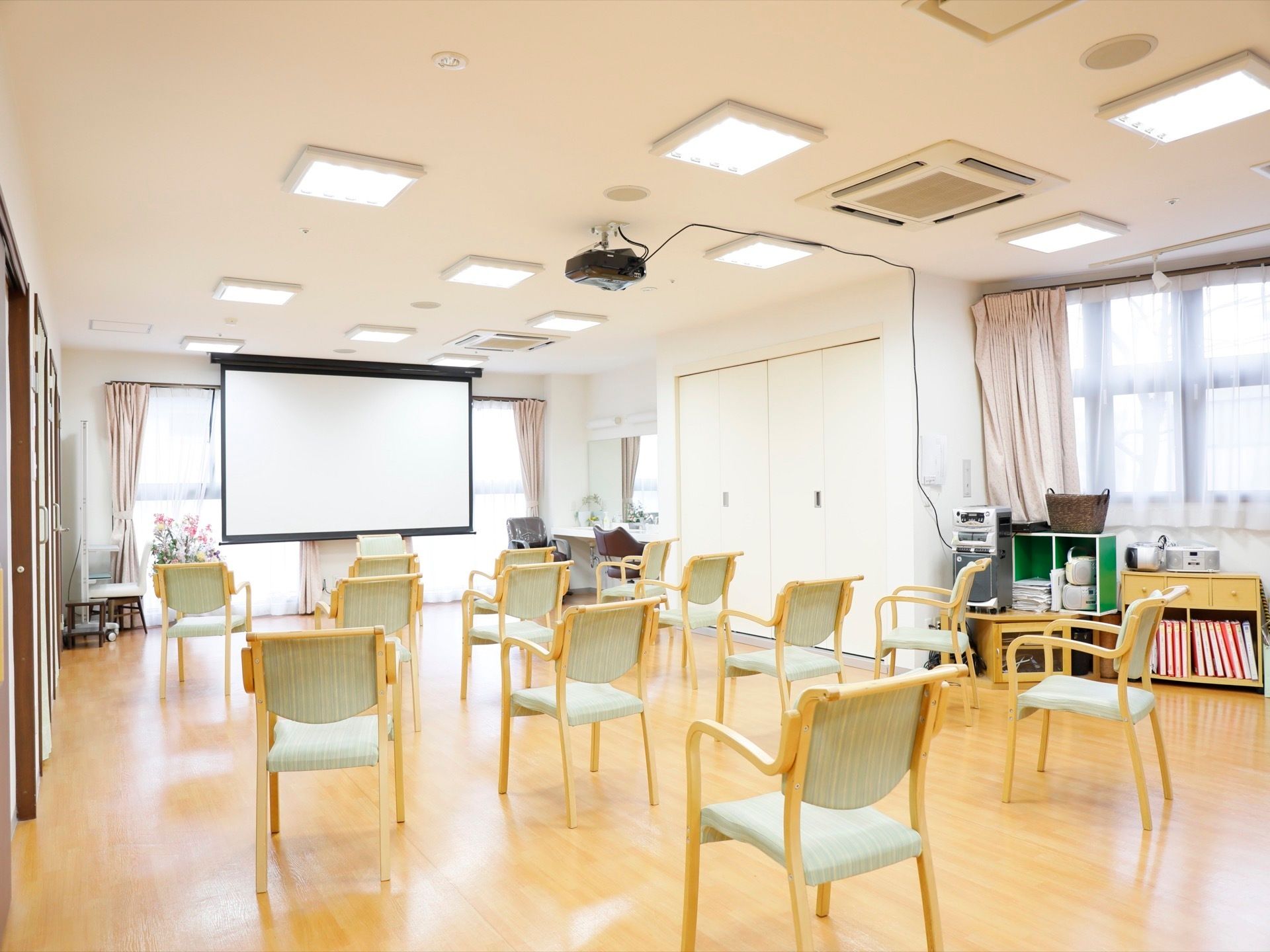 清潔感のある多目的スペース。ひじ掛け付きの椅子を配置している。天井にプロジェクタが設置されており、映画などを鑑賞できる。