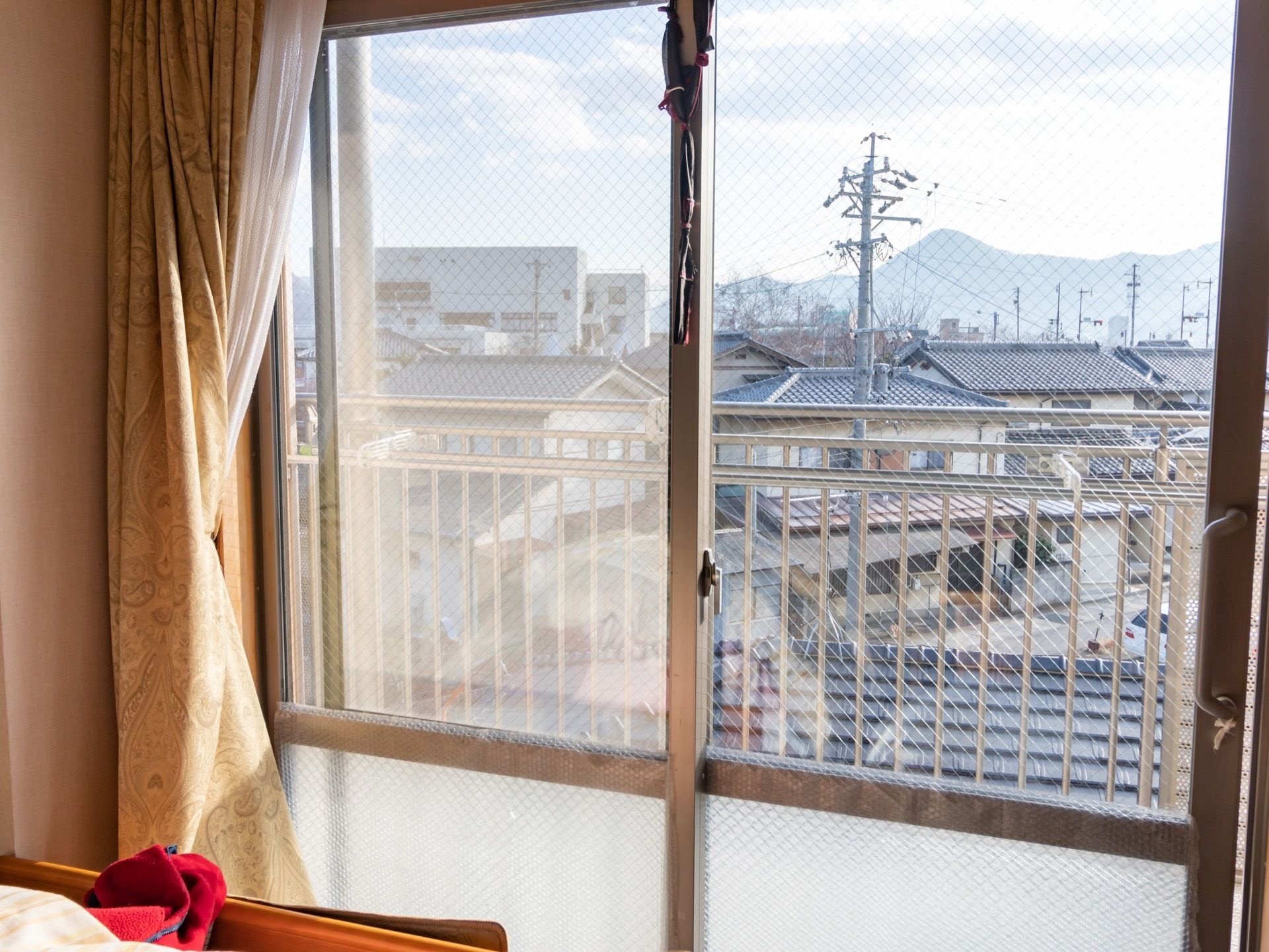居室の突き当たりに掃き出しの窓があり、外に瓦屋根の街並みが広がっている。遠くの方には山も見えている。